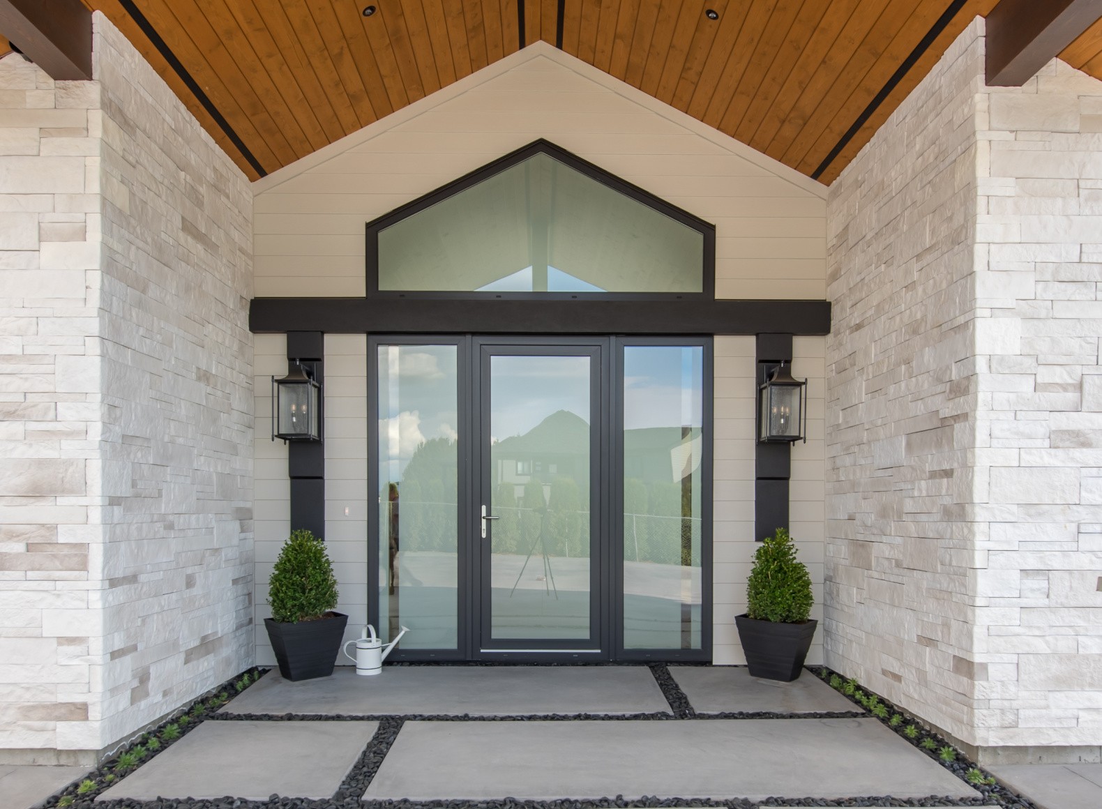 Double glass front-entry doors beneath a stone portico